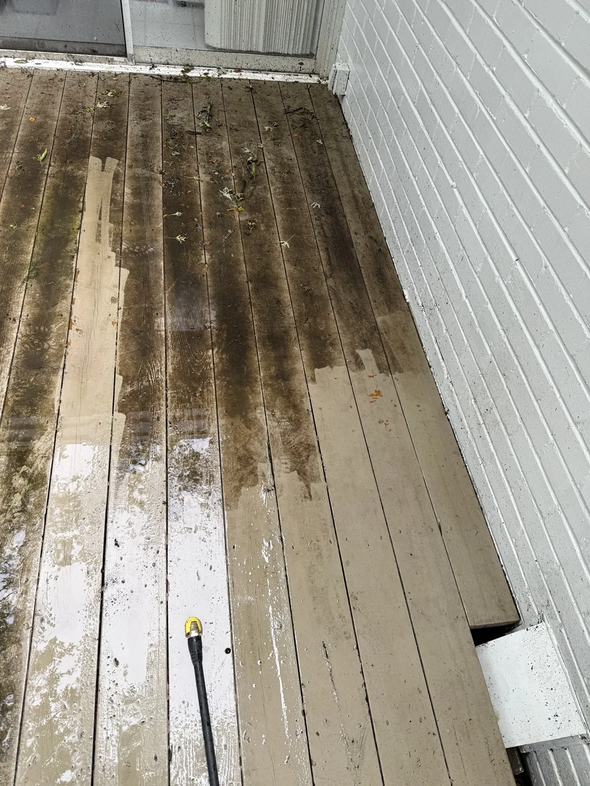 Deck pressure washing in progress showing clean and dirty areas